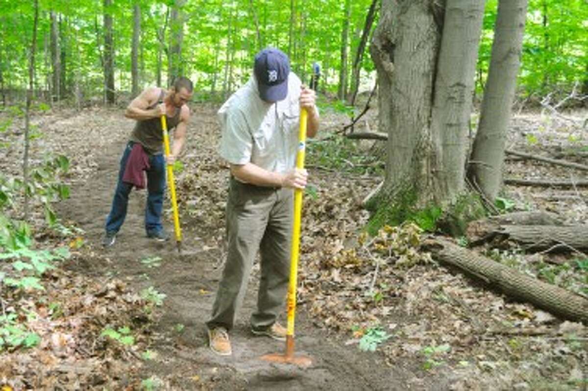 Mark Macoun, of Chicago (left), and Mark Deode, of Detroit, used McLeods to pack down dirt at the Arcadia Dunes C.S. Mott NaturePreserve.
