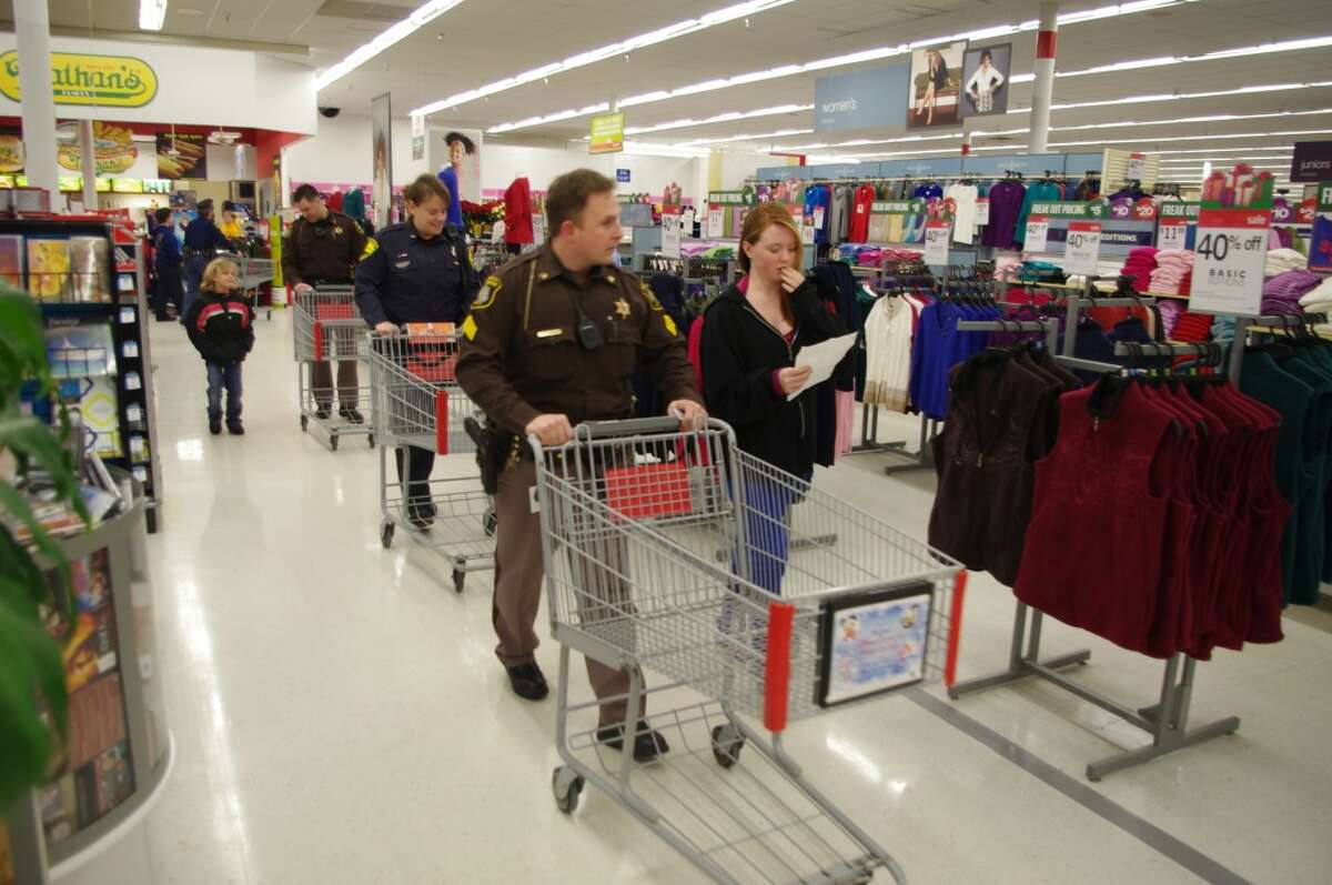 The shoppers grapped their carts and set about the task of shopping for 19 families. In the front here is Manistee County Sheriff’s Deputy Paul Woroniak, shopping with Savannah Foster. (Dave Yarnell/News Advocate)