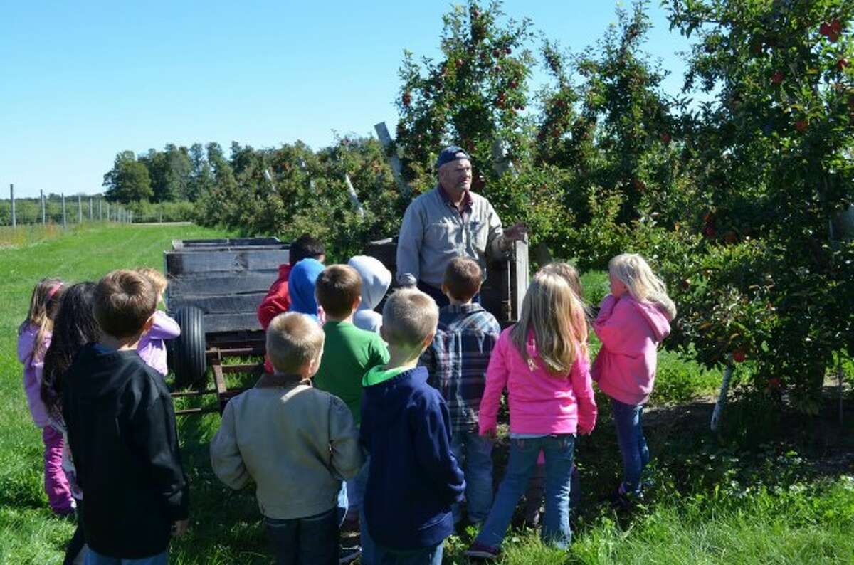 Apple farmer Dave Smeltzer talks with students from Ann Edmondson's first grade class at Bear Lake Schools about how apples are grown.