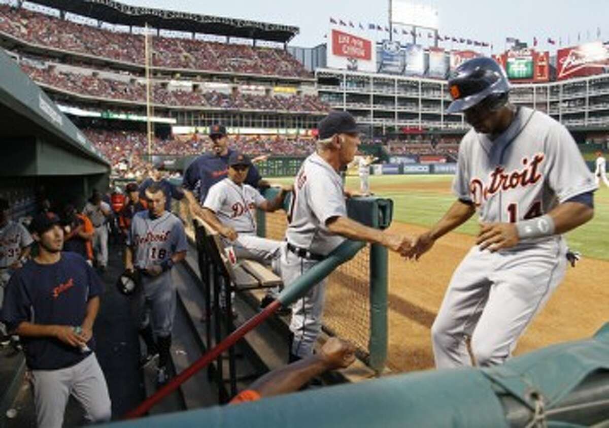 Tigers center fielder Austin Jackson (14) scores on a Miguel Cabrera hit in the the fourth inning drawing a greeting from Detroit manager Jim Leyland in the dugout at Rangers Ballpark in Arlington on Friday. (Paul Moseley/Fort Worth Star-Telegram/MCT)