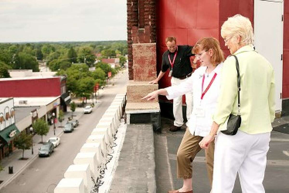 Manistee Mayor Colleen Kenny (center) and Big Rapids Clerk Roberta Cline look over the edge of the top of the Nisbett Building. A tour of the Nisbett and Fairman buildings was the final stop on a day-long tour of Big Rapids as part of a mayor exchange program between the two cities. (Pioneer News Group File Photo)