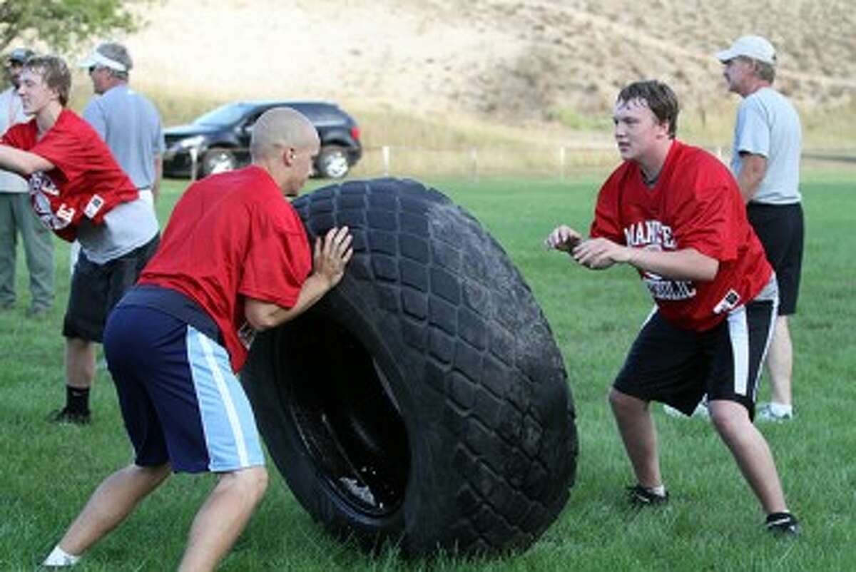 Manistee Catholic Central’s Jeremy Bigalke (left) and Cory Cabot team up for a drill using a large tire during the first day of practice on Monday. (Matt Wenzel/News Advocate)