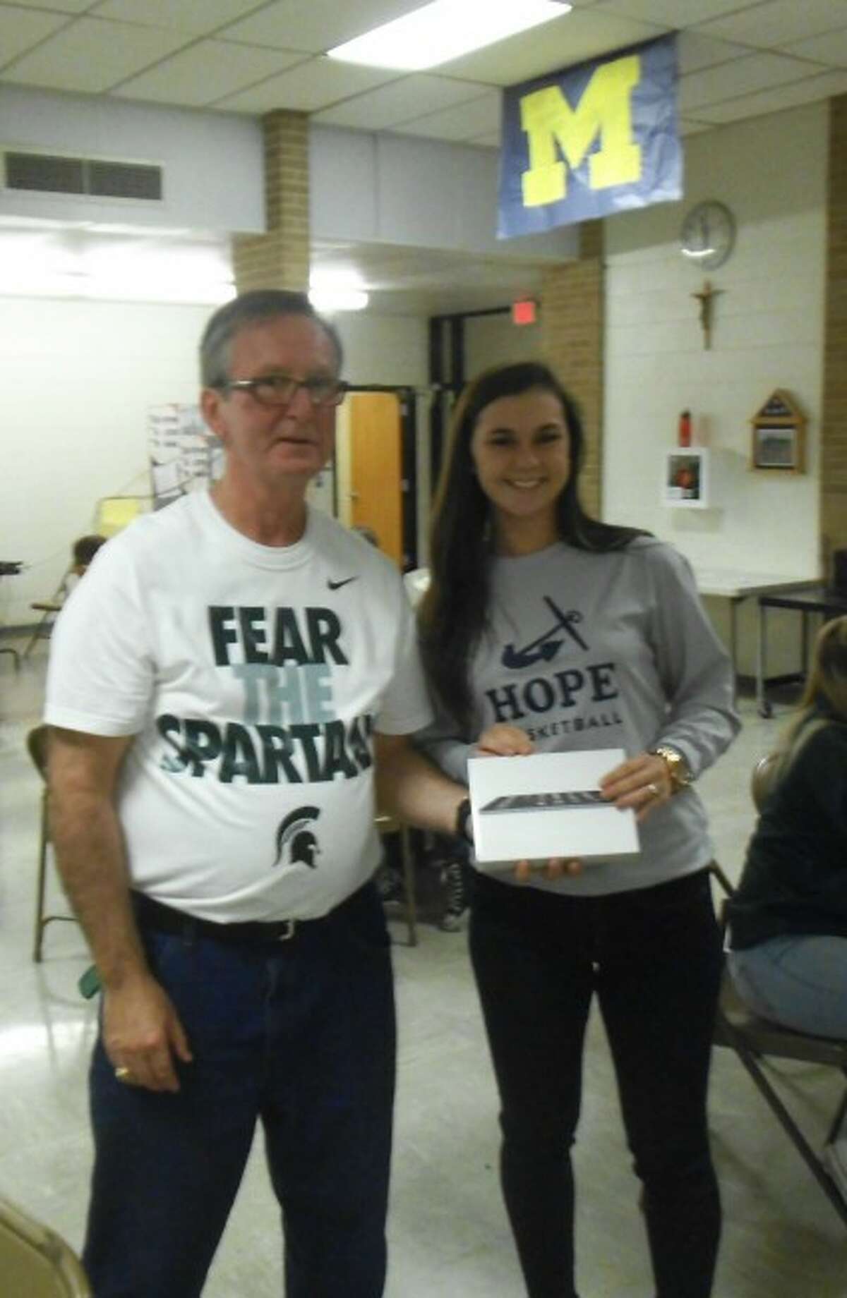 Manistee Catholic Central dean of students Ed Kolanowski presents Jodi Janowiak with the iPad mini she won in the drawing during College Application Week.