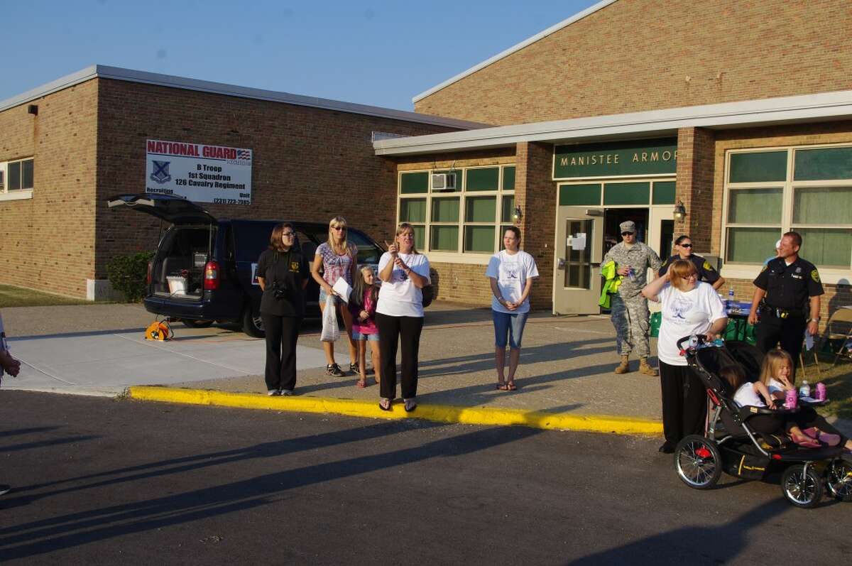 Tami Schultz (standing on curb) makes announcements before last year's Bravo Troop 5K run. She is the president of the troop's family readiness group, which is sponsoring the run to be held at 8 a.m. Saturday at the armory. Other Bravo Troop family members can be seen in the photo. (News Advocate File Photo)