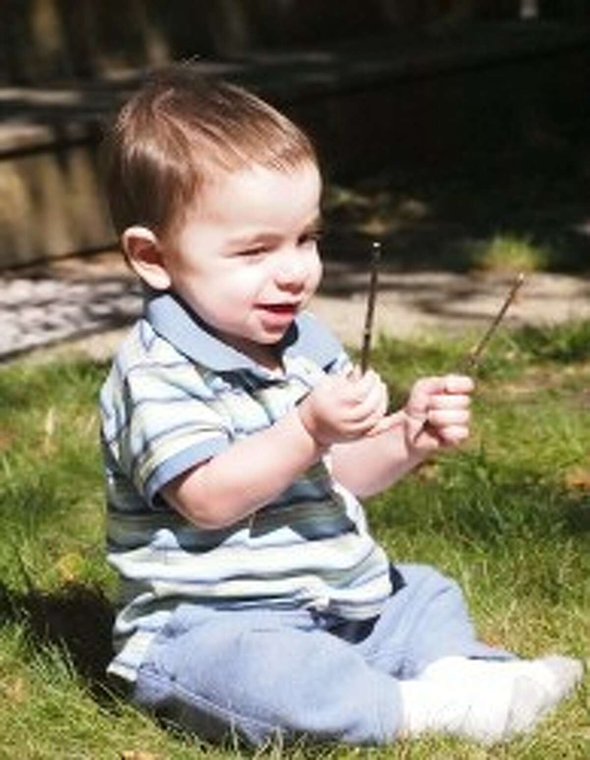 Owen Pointer, who will turn 2 years old next month, plays with two sticks in his grandparent's backyard. This week Owen and his family celebrated the one-year anniversary of him getting a new, healthy heart. (Courtesy Photos/Jeanne Barber)
