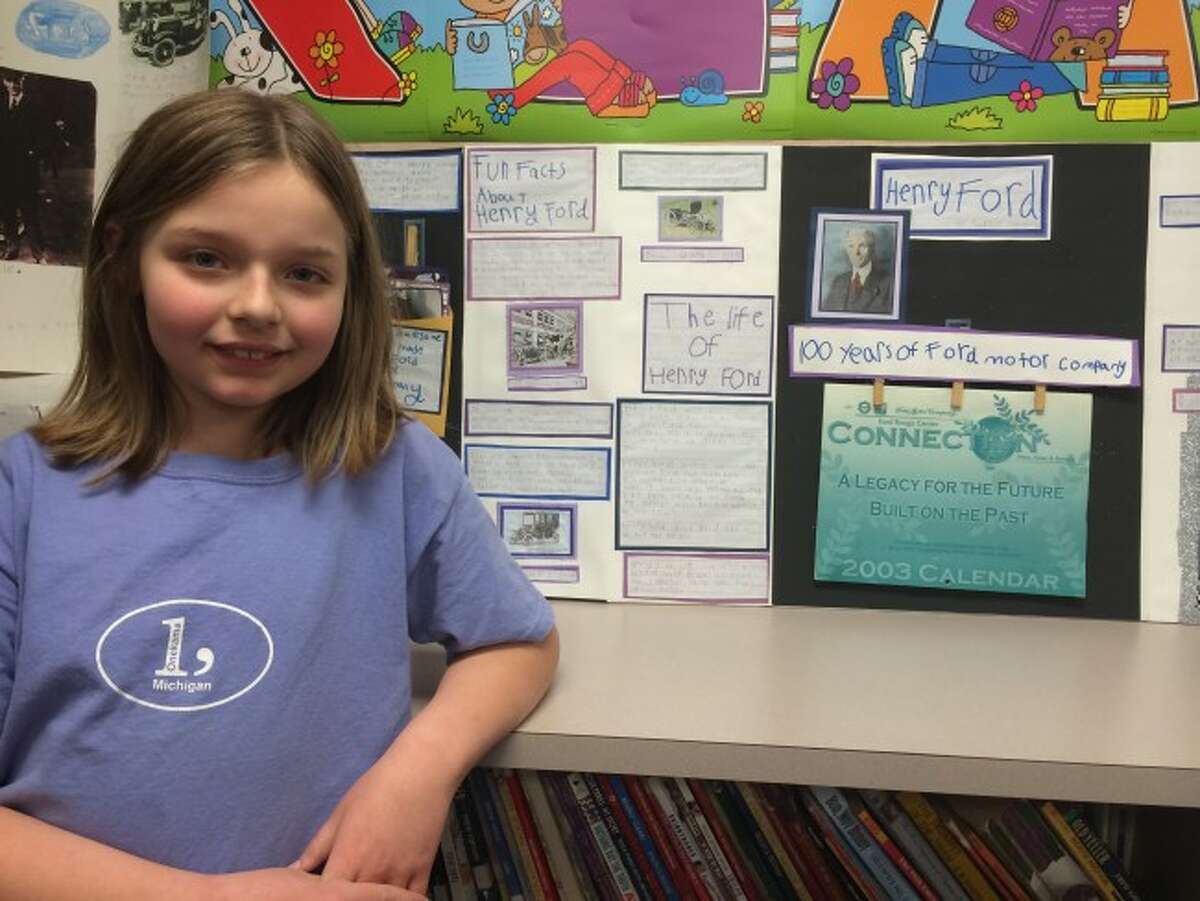 Onekama Consolidated Schools third grade student Aubrey Johnson proudly shows off her display on Henry Ford. It was part of an assignment students did on honoring Michigan's heroes.