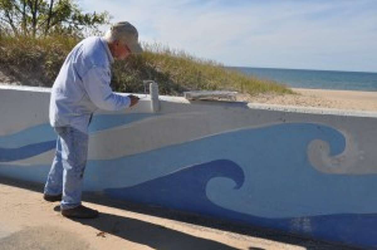 Dick Albee was one of several volunteers who repainted the fish wall at First Street Beach on Monday.