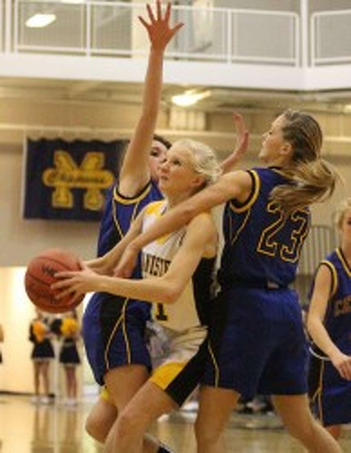 Annie Fuller (middle) draws a foul on MCC’s Payton Bladzik (23) during the first quarter. (Matt Wenzel/News Advocate)