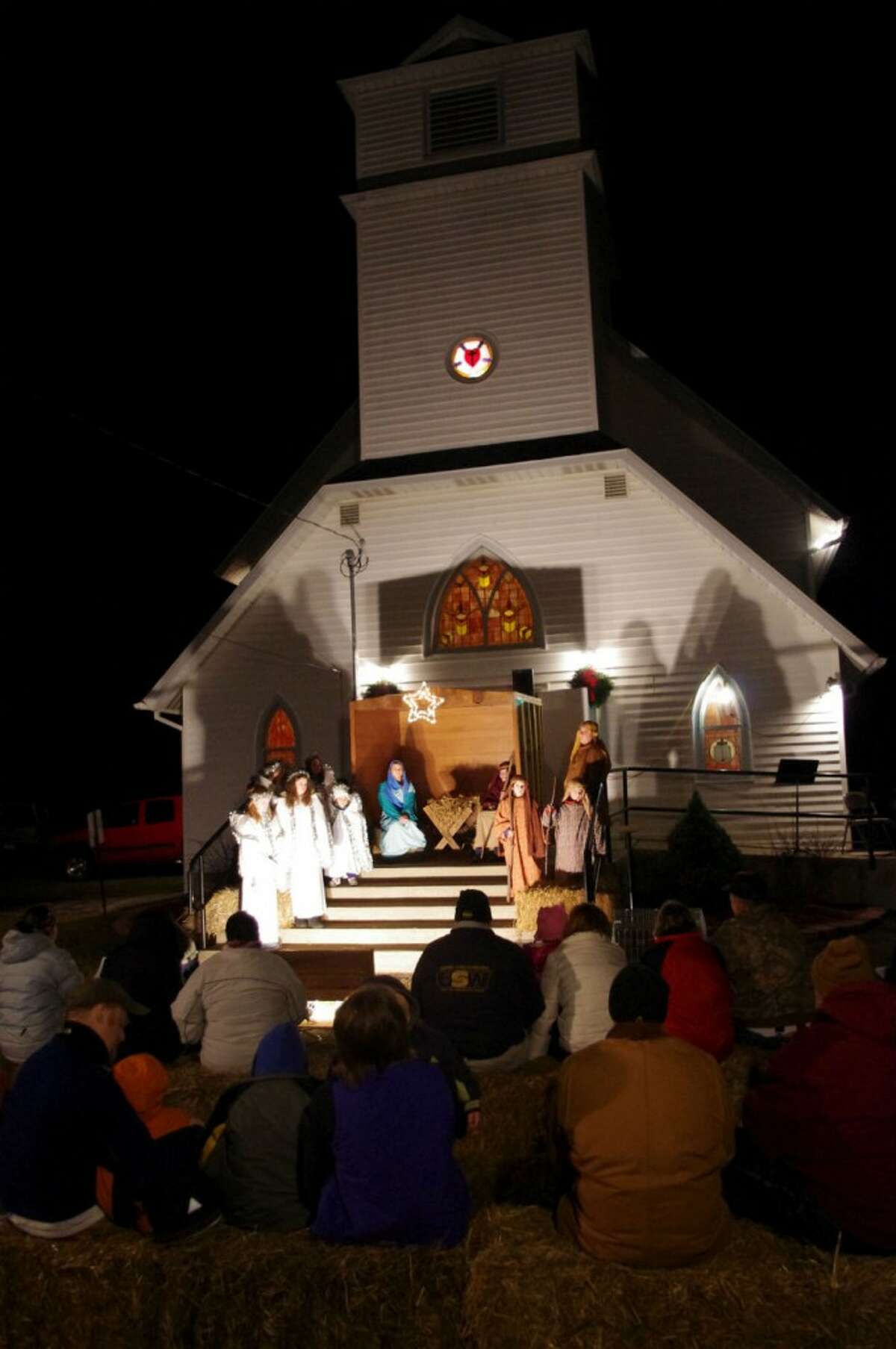 The congregation sat on bales of straw to watch the 23rd annual Norwalk Lutheran Chruch live nativity. (Dave Yarnell/News Advocate)
