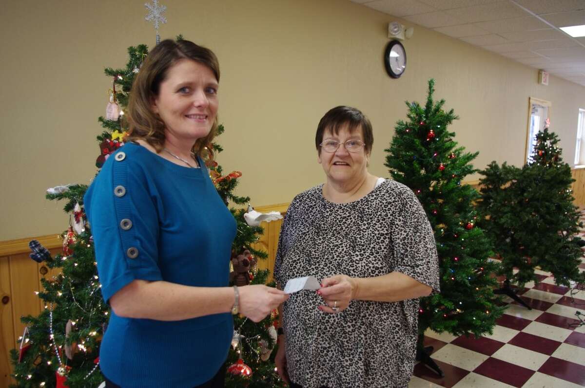 Julie Ingison from the Manistee office of FiveCAP visited the Norman Township Community Center on Tuesday to accept a check from Char Zunker, president of the Wellston Boosters, for the Toys for Tots/Gifts for Teens program. The Wellston Boosters are also inviting the area children to come to the Norman Township Community Center to visit with Santa on Saturday from 6 to 7:30 p.m. (Dave Yarnell/News Advocate)