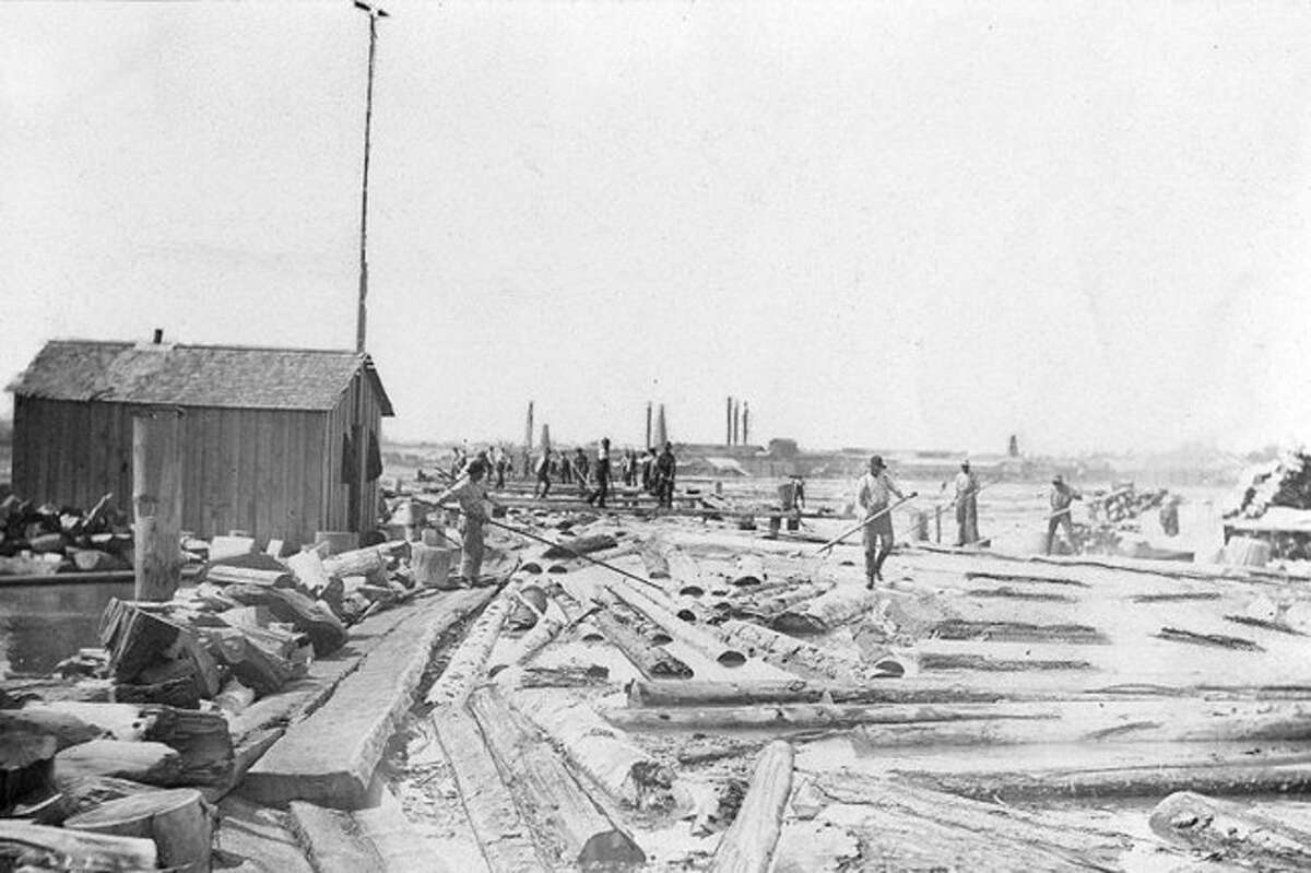 Workers at a local sawmill sort logs out in the water in preparing them to be processed at the mill in this 1890s photograph.