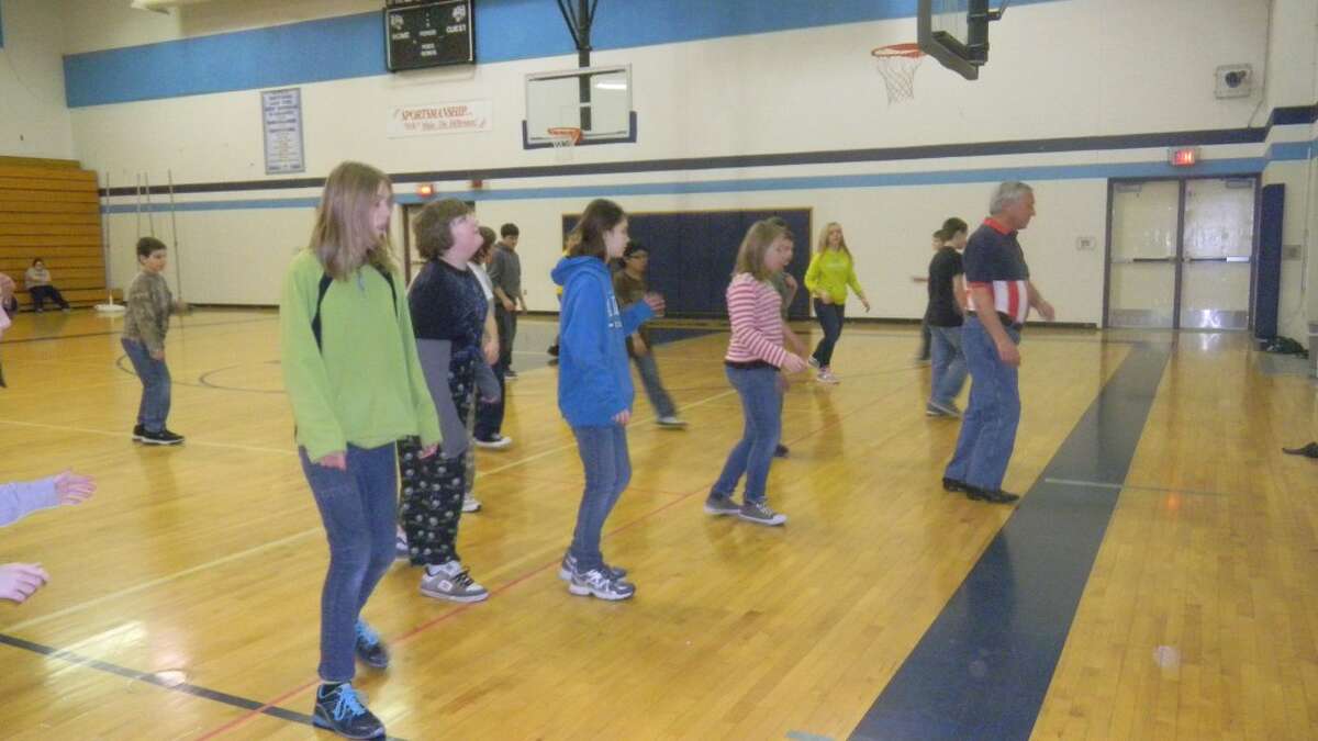 Marv Scarlata of the Just Country Kickin’ Line Dance Club leads a group of Brethren sixth grade students through their moves in line dancing.
