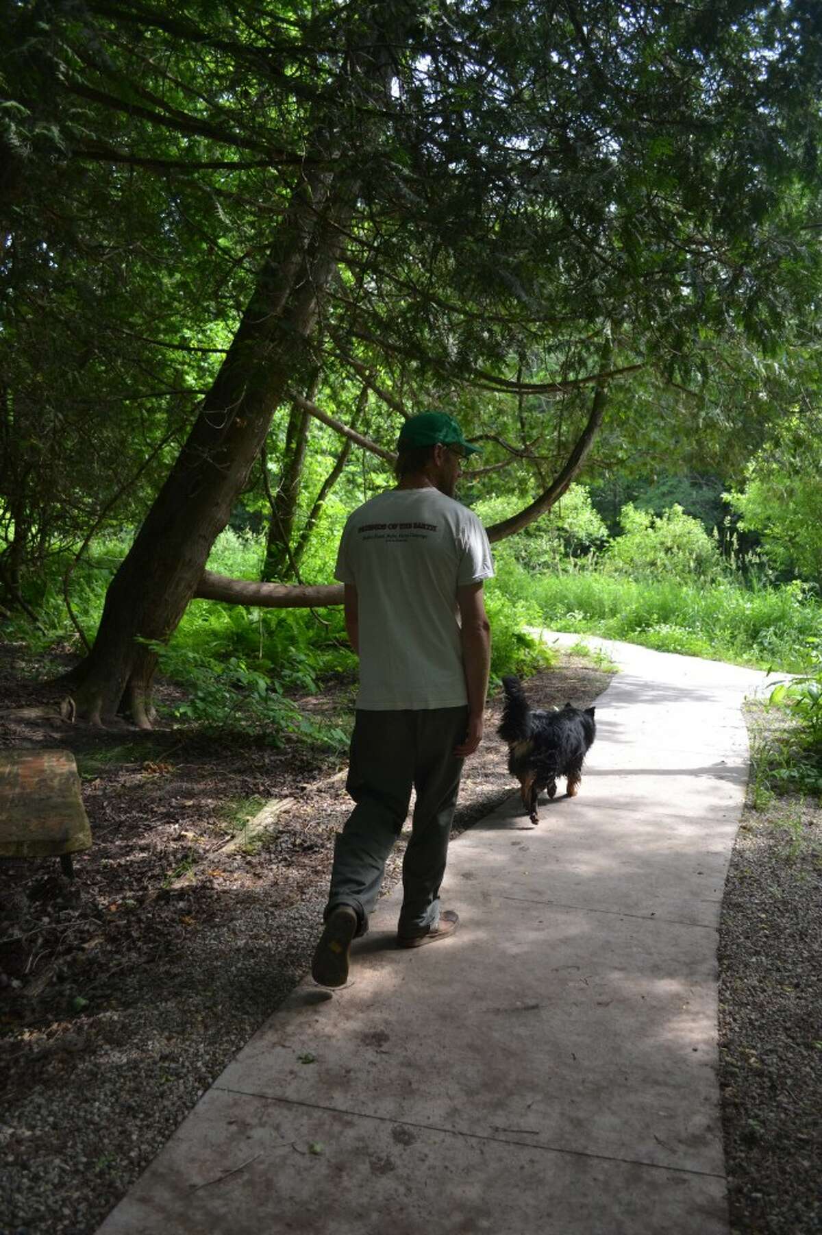 Erik Kinzinger, president of the Spirit of the Woods Conservation Club, walks with his dog Mabel along “Mickey’s Trail,” a universally-accessible pathway on club land. (Meg LeDuc/News Advocate)