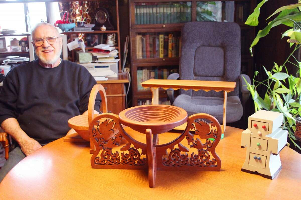 MASTER OF HIS CRAFT: Jim Pylman, 79, of Evart, poses with a small selection of items he has made for his own use or pleasure. Furniture, picture frames, chests, toys, table centerpieces, collapsible baskets and more have been created throughout the years by his skill and talent. (Karin Armbruster/Herald Review photo)