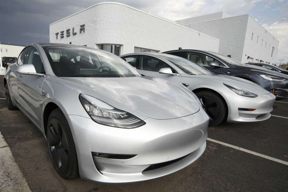 FILE- In this July 8, 2018, photo 2018 Model 3 sedans sit on display outside a Tesla showroom in Littleton, Colo. On Tuesday, Jan. 1, 2019, the federal credit for Tesla buyers dropped from $7,500 to $3,750. It will gradually be phased out this year. (AP Photo/David Zalubowski, File)