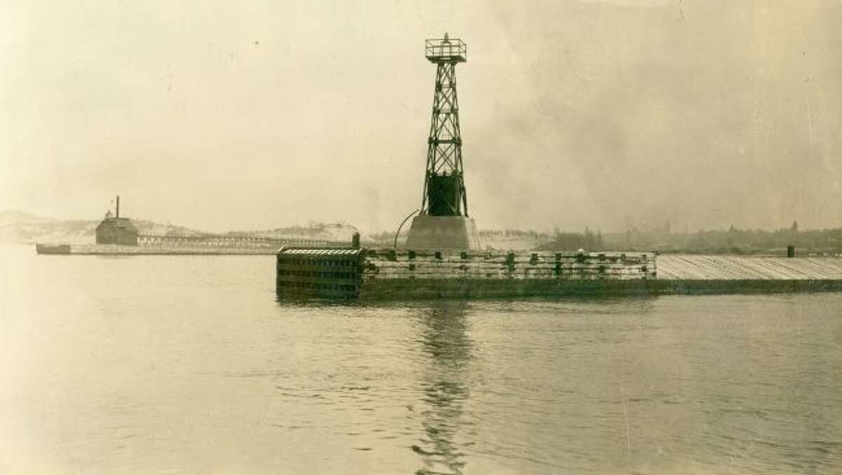 Shown is the the two break walls and lighthouses located at the Manistee Harbor entrance in the early 1900s.