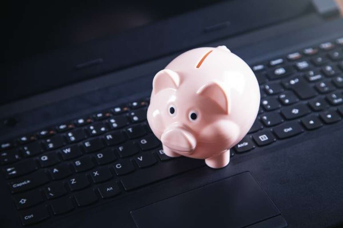 A piggy bank resting on a laptop keyboard. (Dreamstime/TNS)