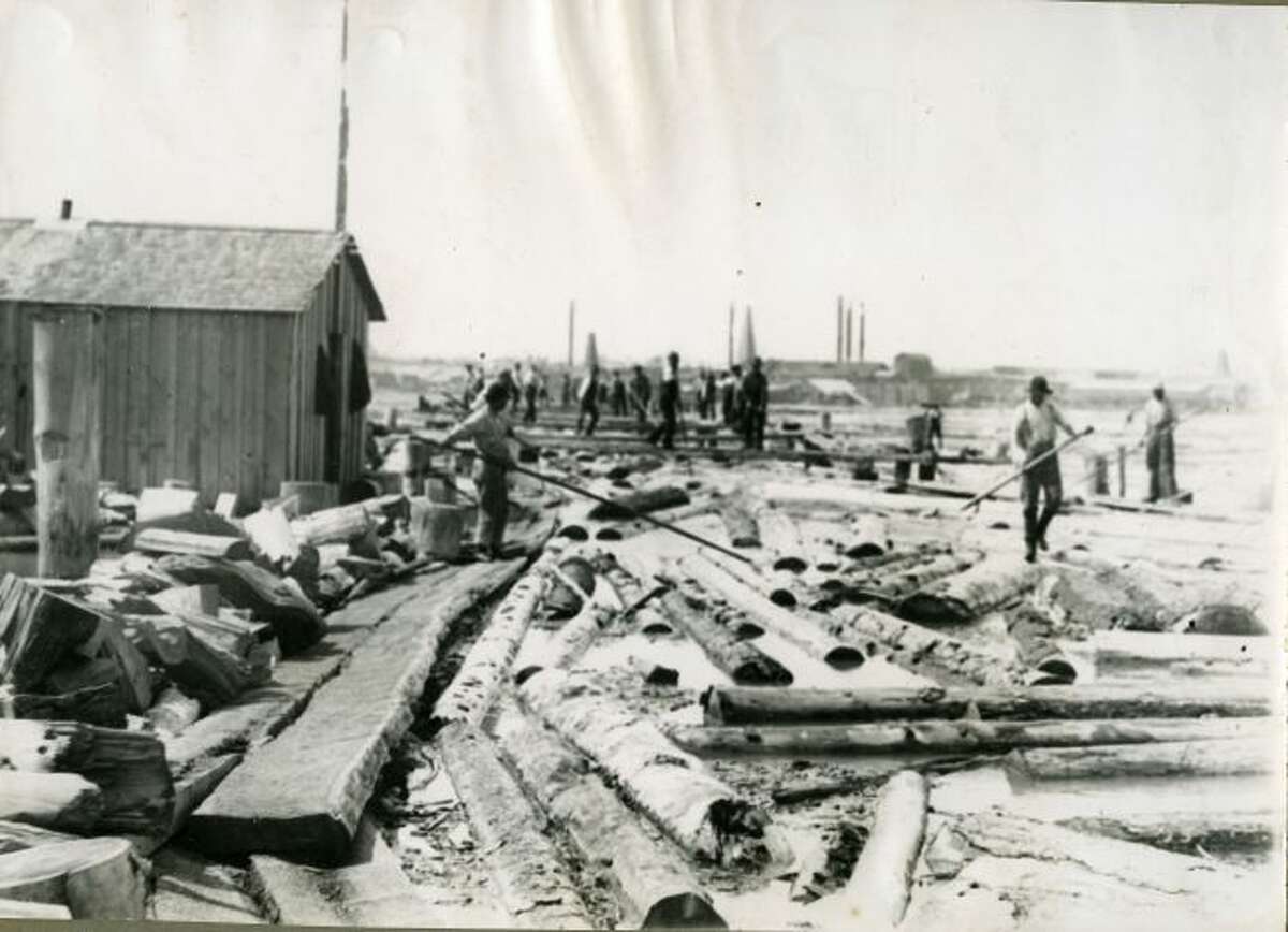 Log sorters move the logs belonging to their particular mill so they can be processed in this 1890s photograph.