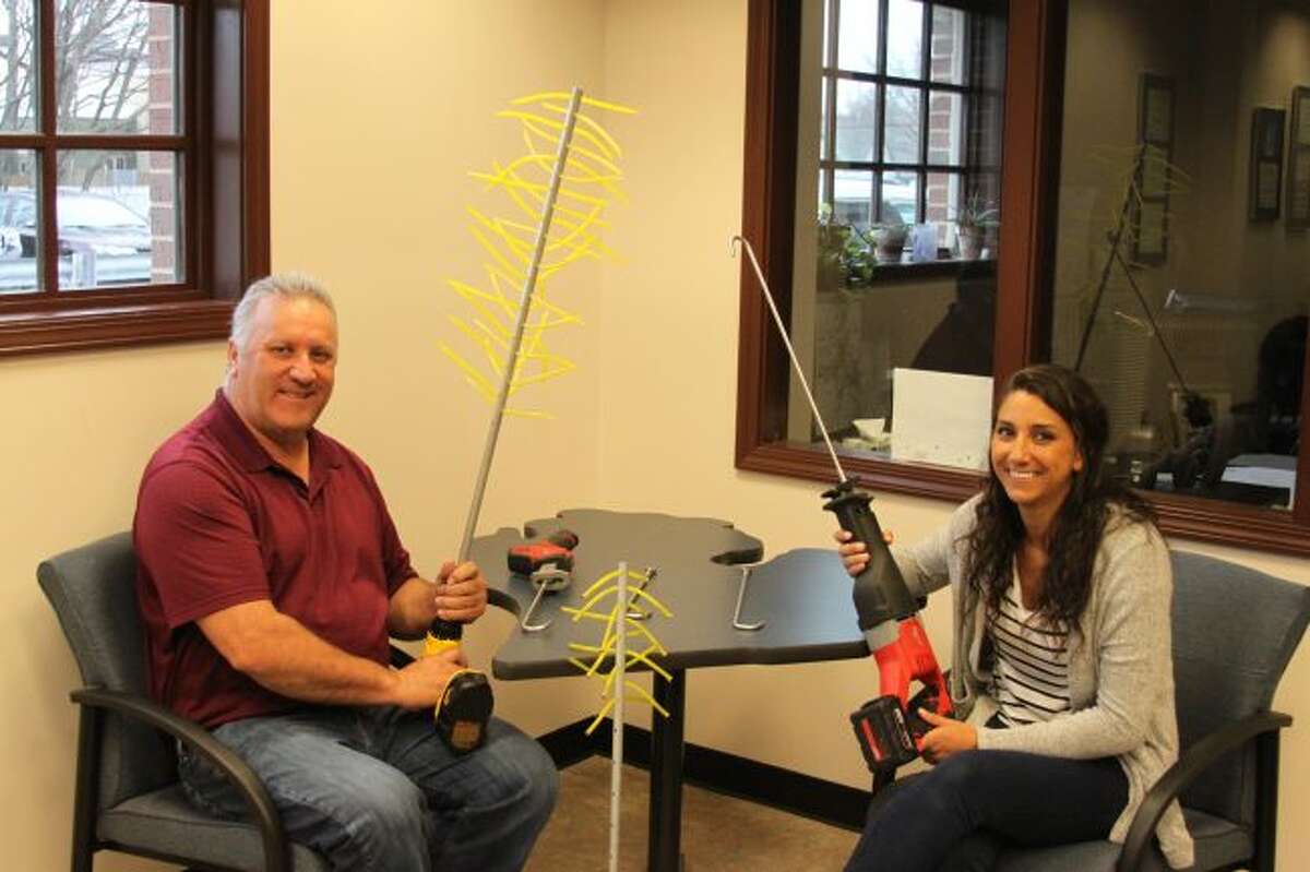 Manistee resident Phil Miller and his daughter Amber Worch show off two devices they have patented and are selling that can be used in the fruit and Christmas tree farming business. Phil is holding "The Cinch" that can be used to remove excess blossoms that can be used to remove excess blossoms that allows trees to produces bigger and better fruit. It can also be used to remove pine cones from Christmas trees. Amber is holding "The Hook Thinner" which can be placed around a fruit tree limb to gently thin out the product to produce better fruit.