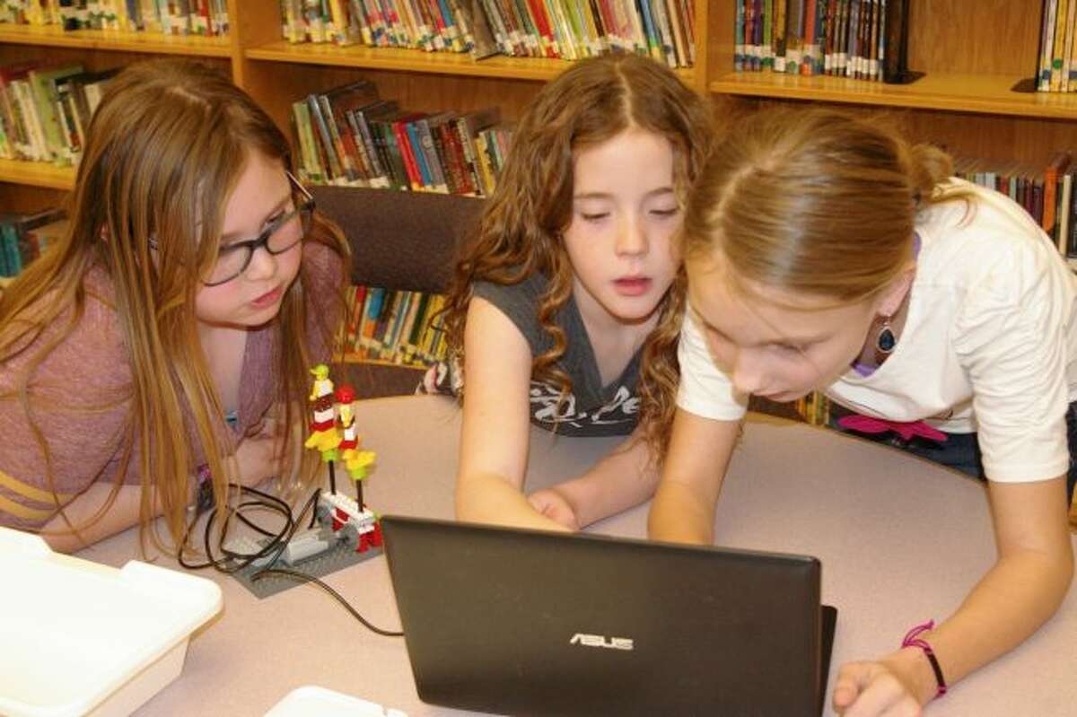 Onekama Consolidated Schools students Anna Bradford, Hailey Hart and Jennifer Kmiecik work on a project on their laptop computer. Students at Onekama Consolidated Schools scored higher than average in state tests as compared to other schools in the state.