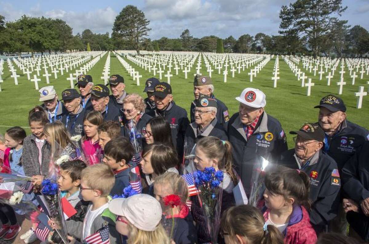 World War II veterans from the United States pose with local school children at the Normandy American Cemetery in Colleville-sur-Mer, Normandy, France, Monday, June 3, 2019. France is preparing to mark the 75th anniversary of the D-Day invasion which took place on June 6, 1944. (AP Photo/Rafael Yaghobzadeh)