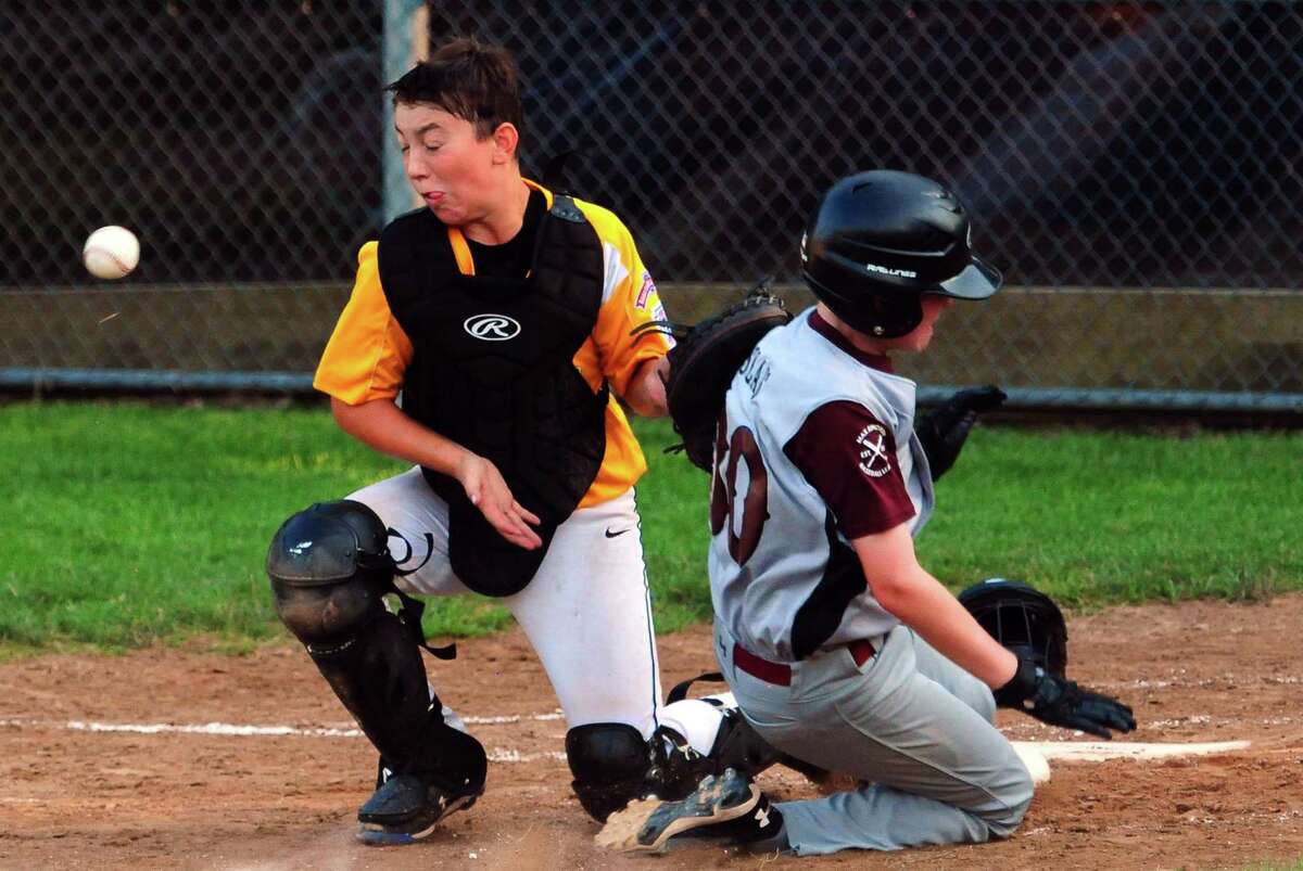 North Haven's John Slais slides into home plate as Madison catcher Paul Calandrelli misses the ball for the tag during little league baseball action in Willimantic, Conn., on Tuesday July 30, 2019.