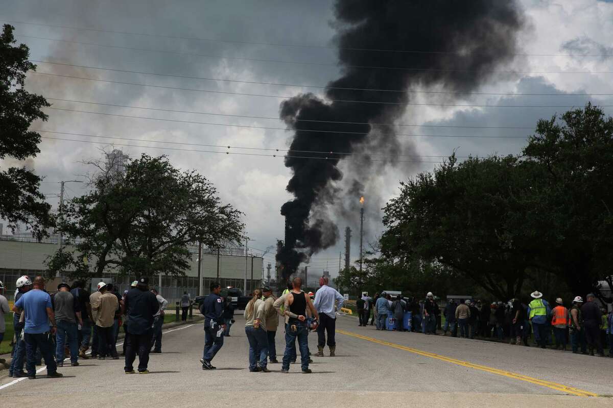 Evacuated ExxonMobil workers take a break or watch the fire from the Baytown Olefins Plant entrance on Wednesday , July 31, in Baytown.