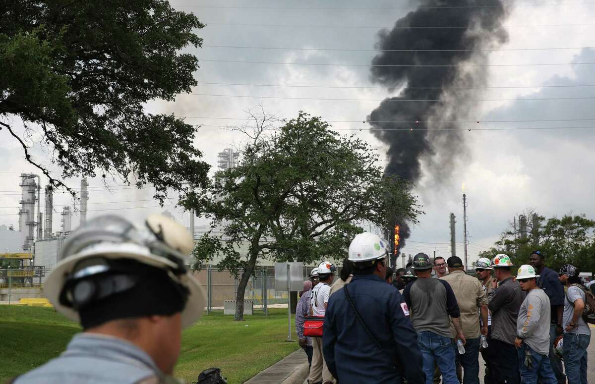 Evacuated ExxonMobil workers take a break or watch the fire from the Baytown Olefins Plant entrance on Wednesday , July 31, in Baytown.