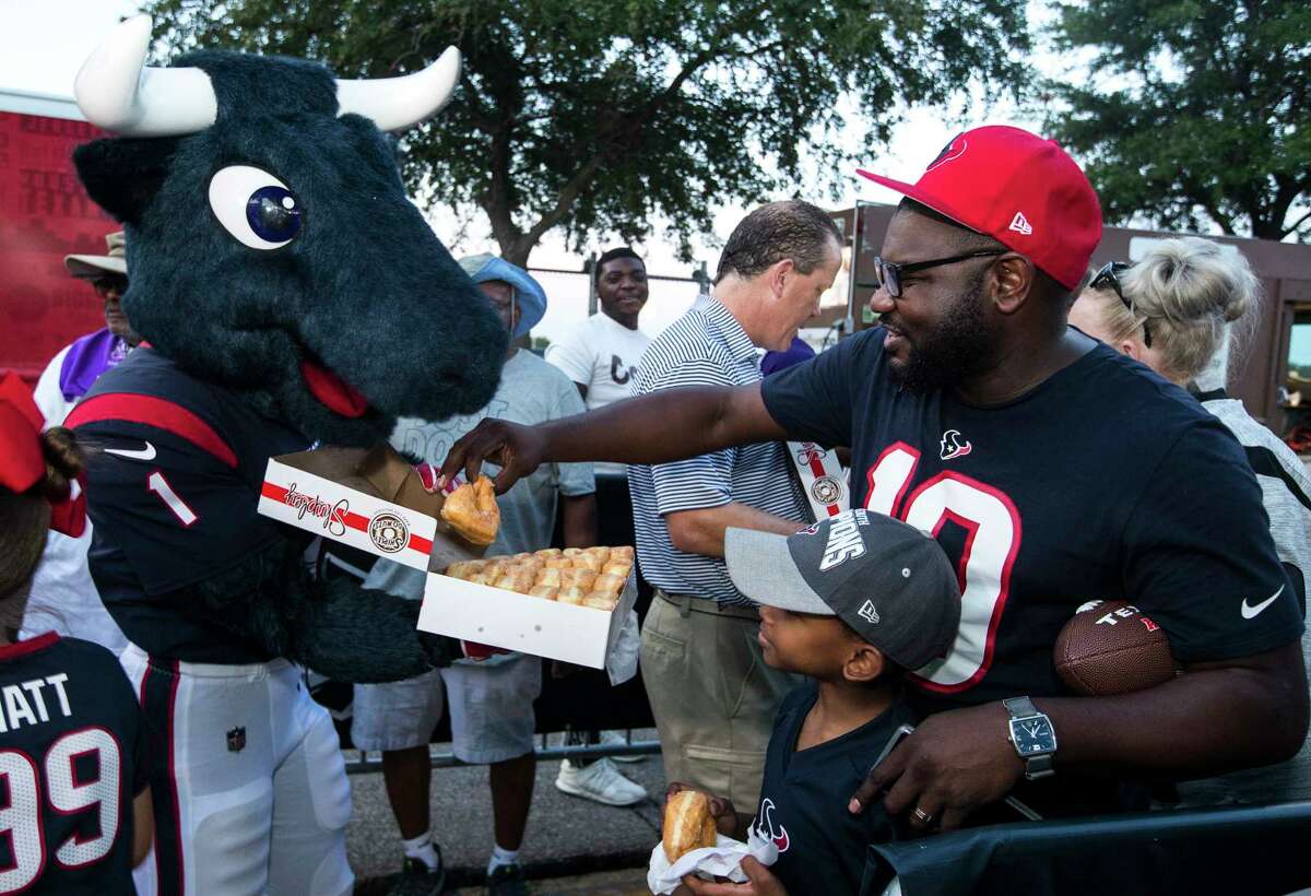 Houston Texans mascot Toro hands out donuts to the early-arriving fans in line to watch the Texans first open practice of training camp at the Methodist Training Center on Thursday, Aug. 1, 2019, in Houston.