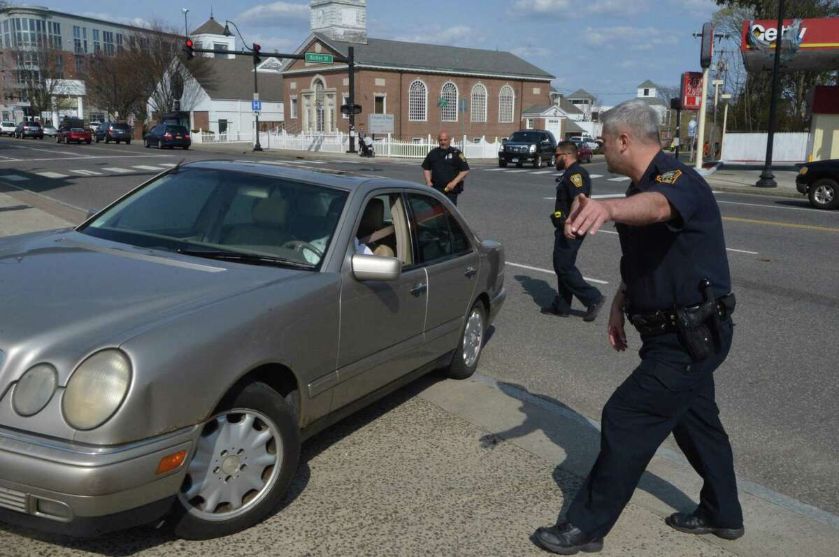 Norwalk Police Officers direct a car out of traffic on West Ave as Officer Jamile Wright points the driver into a parking lot and will issue her a ticket for distracted driving in 2015 in Norwalk, Conn.