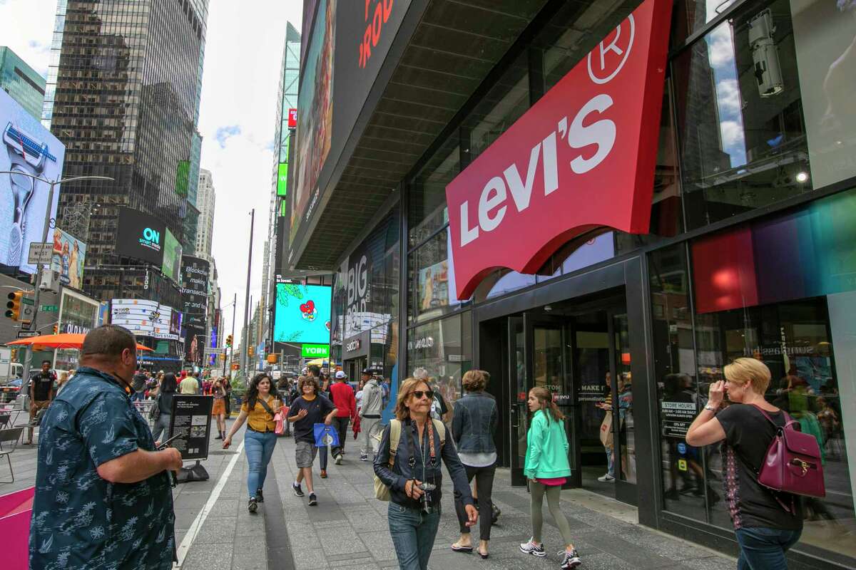 In this June 14, 2019, photo people pass the Levi's store in in New York's Times Square. Levi Strauss & Co.as new flagship in Manhattanas Time Square features larger dressing rooms with call buttons and tailors who can add trims and patches to customersa jeans. (AP Photo/Richard Drew)