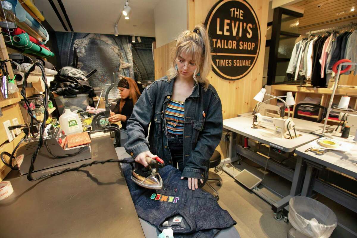 In this June 14, 2019, photo tailors Latoya Henderson, left, and Aly Reinert work in the Levi's Tailor Shop, in the Levi's store, in New York's Times Square. Levi Strauss & Co.as new flagship in Manhattanas Time Square features larger dressing rooms with call buttons and tailors who can add trims and patches to customersa jeans. (AP Photo/Richard Drew)
