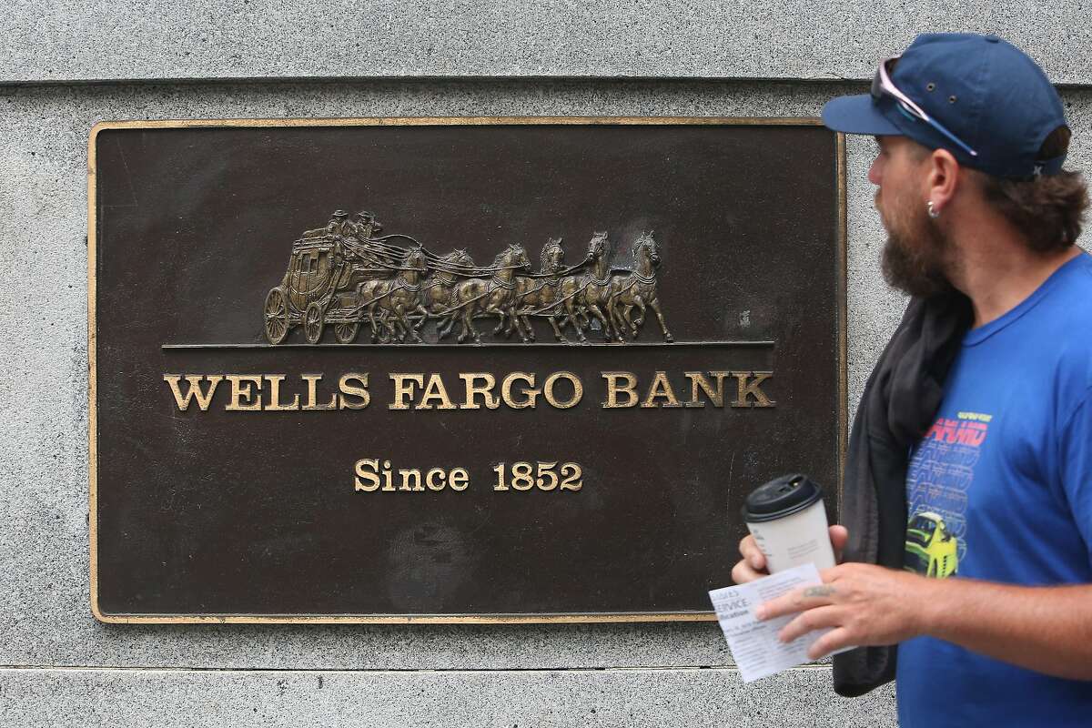 A pedestrian walks past a Wells Fargo bank plaque at 1 Montgomery Street on Tuesday, July 30, 2019 in San Francisco, Calif.
