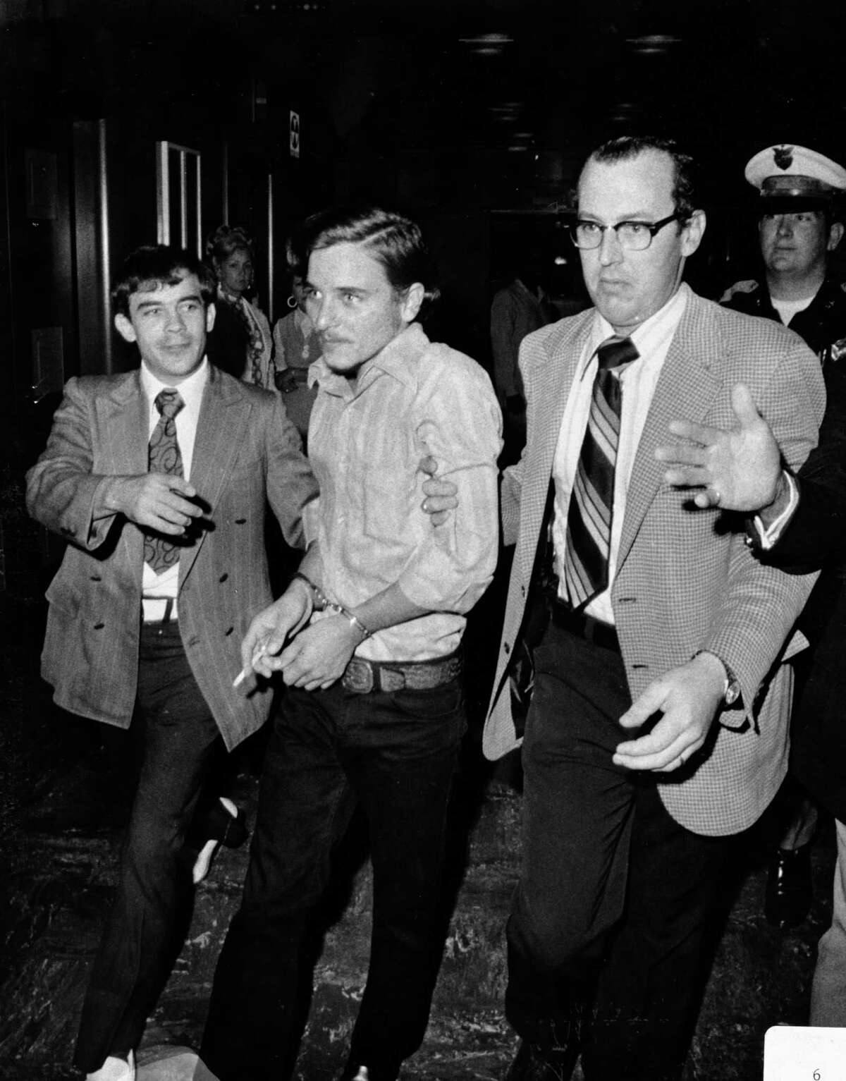 Aug. 13, 1973: A handcuffed Elmer Wayne Henley is escorted by police officers into a courtroom to face murder charges after he killed Dean Arnold Corll. Corll, who was known as The Candy Man, was a serial killer believed to have killed 28 teenage Houston boys, most of whom were lured by then-17-year-old Henley and a third teenage accomplice, David Owen Brooks. The murders came to light when Henley shot Corll Aug. 8, 1973. Henley is currently serving a 594-year sentence in the Texas State Penitentiary in Huntsville.