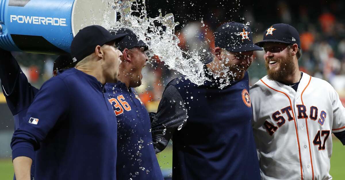 Houston Astros pitchers, from left, Aaron Sanchez, Will Harris (36), Joe Biagini and Chris Devenski (47) get doused with a bucket of water as they celebrate a combined no-hitter against the Seattle Mariners at Minute Maid Park on Saturday, Aug. 3, 2019, in Houston.
