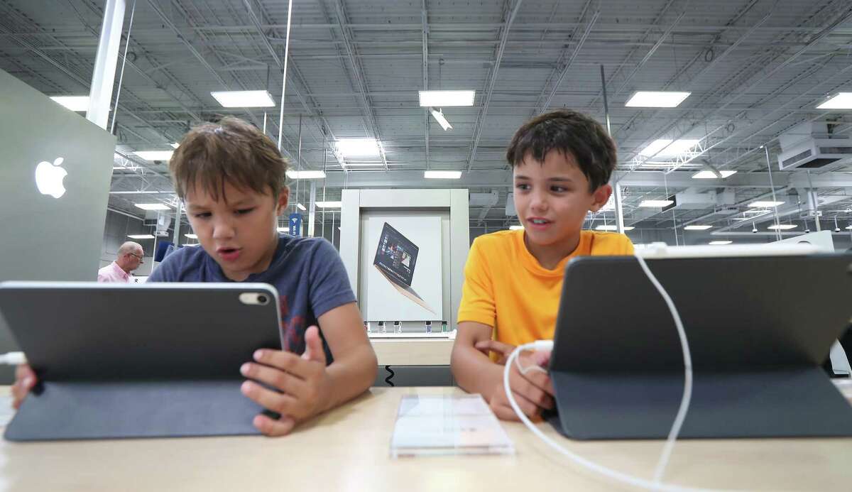 Clive Pilson, 7, (left) and his brother Rohan, 9, look at iPads at Best Buy Wednesday, July 31, 2019, in Houston.