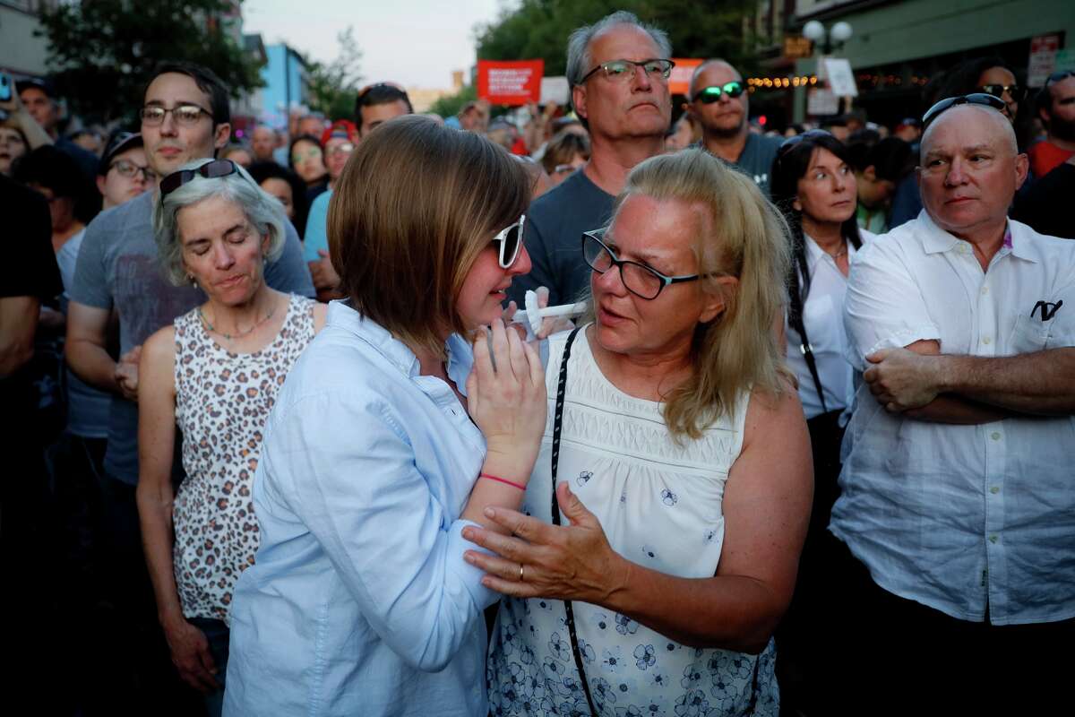 Mourners comfort one another during vigil at the scene of a mass shooting, Sunday, Aug. 4, 2019, in Dayton, Ohio. Multiple people in Ohio have been killed in the second mass shooting in the U.S.