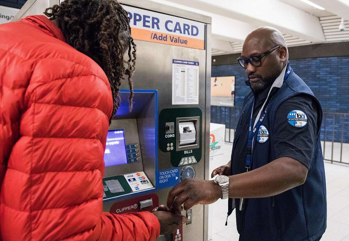 BART Station Agent William Cromartie helps a passenger add fare to their Clipper Card while working the information booth at the 19th Street BART Station in Oakland, Calif. Tuesday, July 2, 2019.