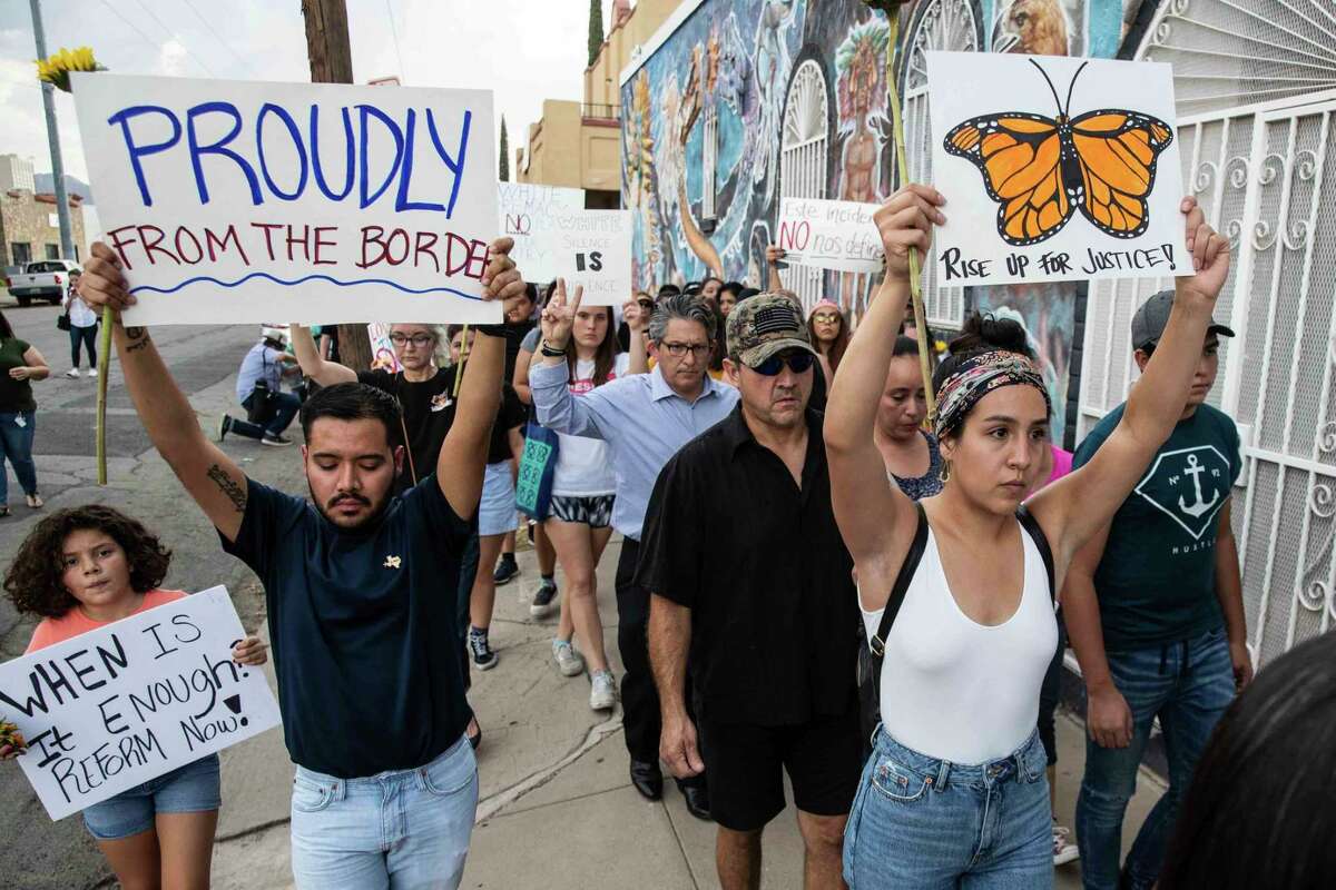 People march in silence Sunday in El Paso, Texas, holding sunflowers and signs to honor the victims of the mass shooting that occurred in Walmart on Saturday.
