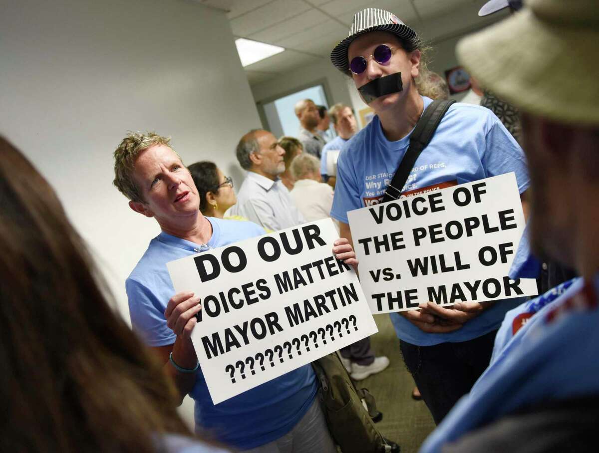 Stamford residents Laurie Doig and Marc Moorash made signs questioning Mayor David Martin's appointment of Chris Murtha as police chief before the Board of Representatives vote at the Government Center in Stamford, Conn. Monday, Aug. 5, 2019.
