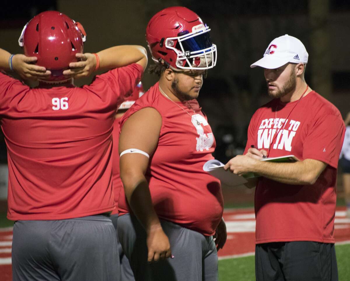 KJ Glaspie, an offensive coach for the Coahoma Bulldogs, speaks with senior Jonathan Schneider, middle, before the first football practice of the season.
