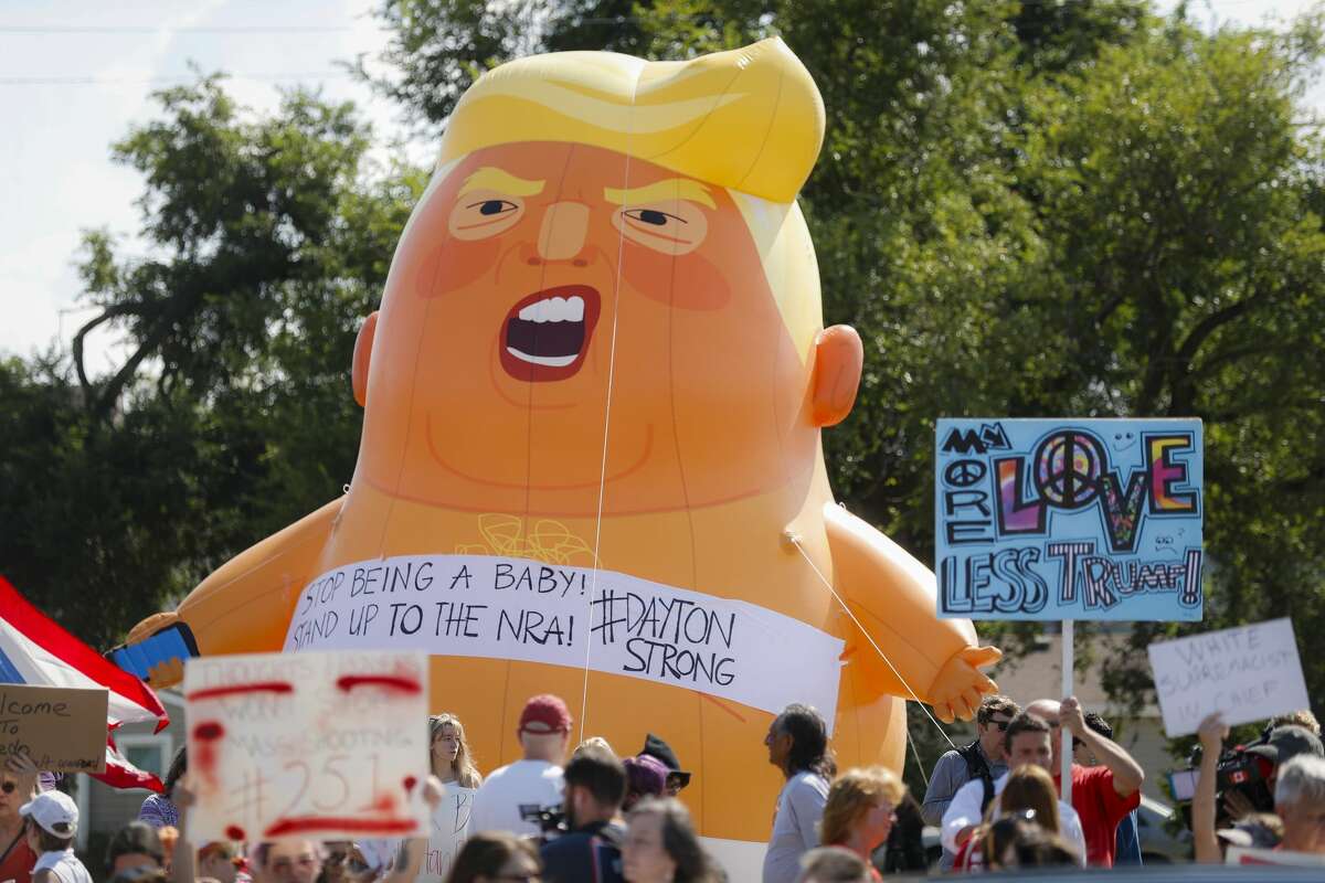Demonstrators gather in front of an inflatable "Baby Trump" to protest the arrival of President Donald Trump outside Miami Valley Hospital after a mass shooting that occurred in the Oregon District early Sunday morning, Wednesday, Aug. 7, 2019, in Dayton, Ohio.