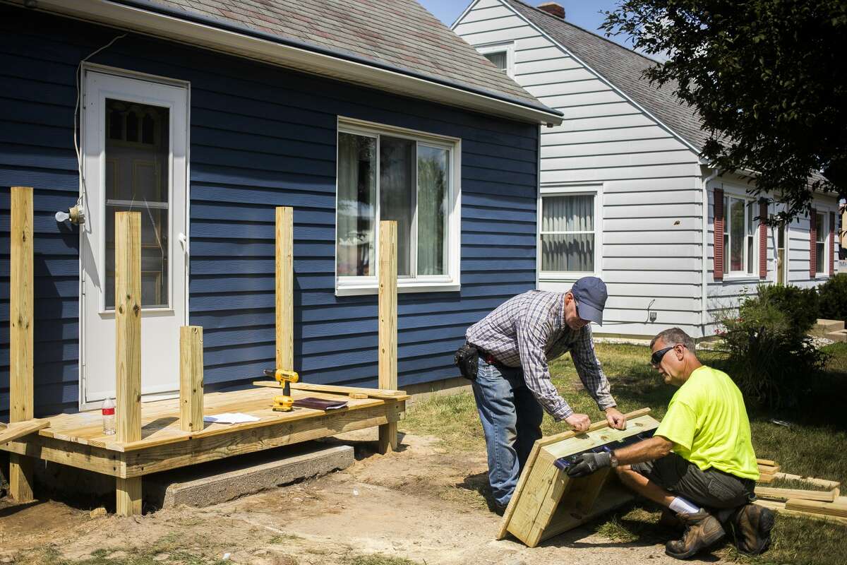 Mike Babcock, left, and Tom Gray, right, construct a front porch while volunteering for Midland County Habitat for Humanity's Neighborhood Revitalization Initiative on Wednesday, Aug. 7, 2019. (Katy Kildee/kkildee@mdn.net)