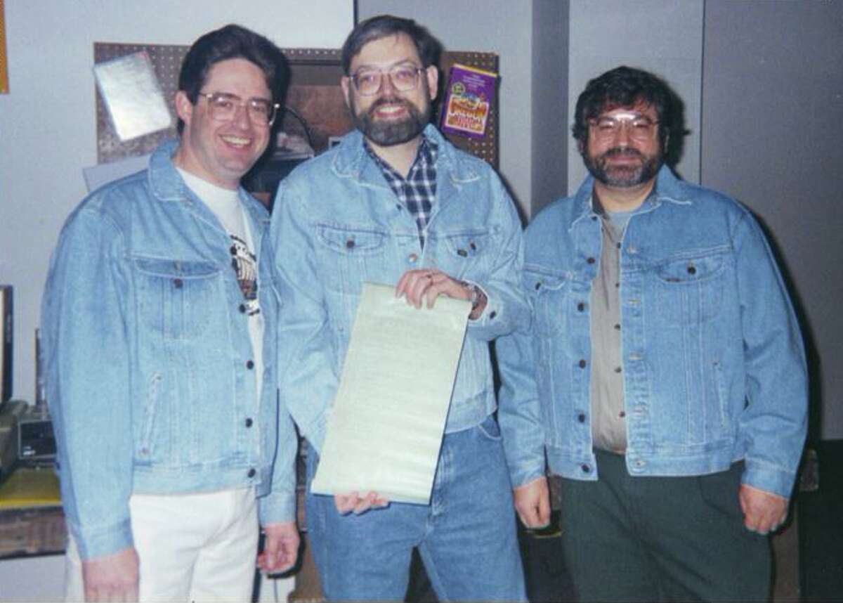 From left to right: Oregon Trail game creators Don Rawitsch, Bill Heinemann, Paul Dillenberger pose (in jean jackets, naturally) with the code for the game in 1995.