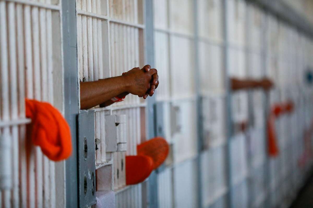 An inmate clasps his hands on the door of his cell at County Jail 4 in the Hall of Justice in San Francisco, California, on Thursday, Nov. 1, 2018.