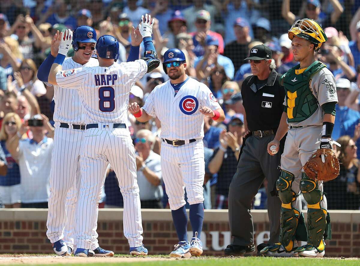 Oakland Athletics catcher Dustin Garneau, right, watches as the Chicago Cubs' Anthony Rizzo, left, congratulates Ian Happ (8) on a grand slam in the fourth inning at Wrigley Field in Chicago on Wednesday, Aug. 7, 2019. The Cubs won, 10-1. (John J. Kim/Chicago Tribune/TNS)