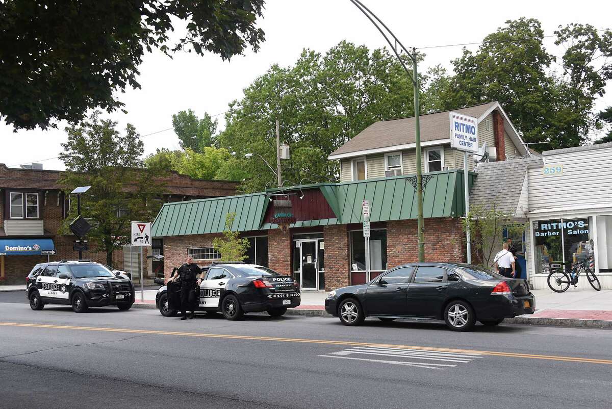Police investigate the scene where two men armed with a gun took money from customers at Ritmo's Barber Salon, at right, at 259 New Scotland Ave. on Thursday, Aug. 8, 2019 in Albany, N.Y. (Lori Van Buren/Times Union)