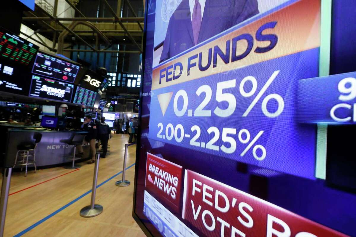 A television monitor on the floor of the New York Stock Exchange headlines the Federal Reserve Board’s decision on July 31 to cut its key interest rate for the first time in a decade.