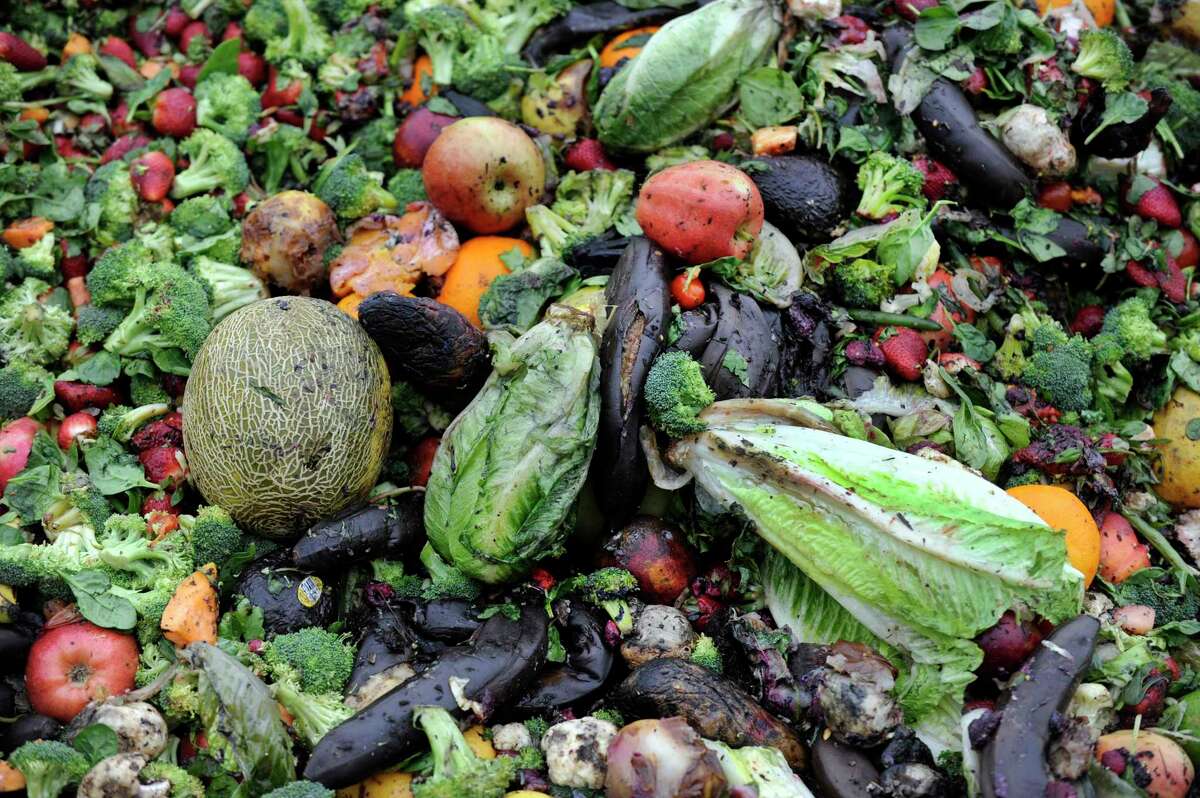 Fruits and vegetables sit in a compost pile.