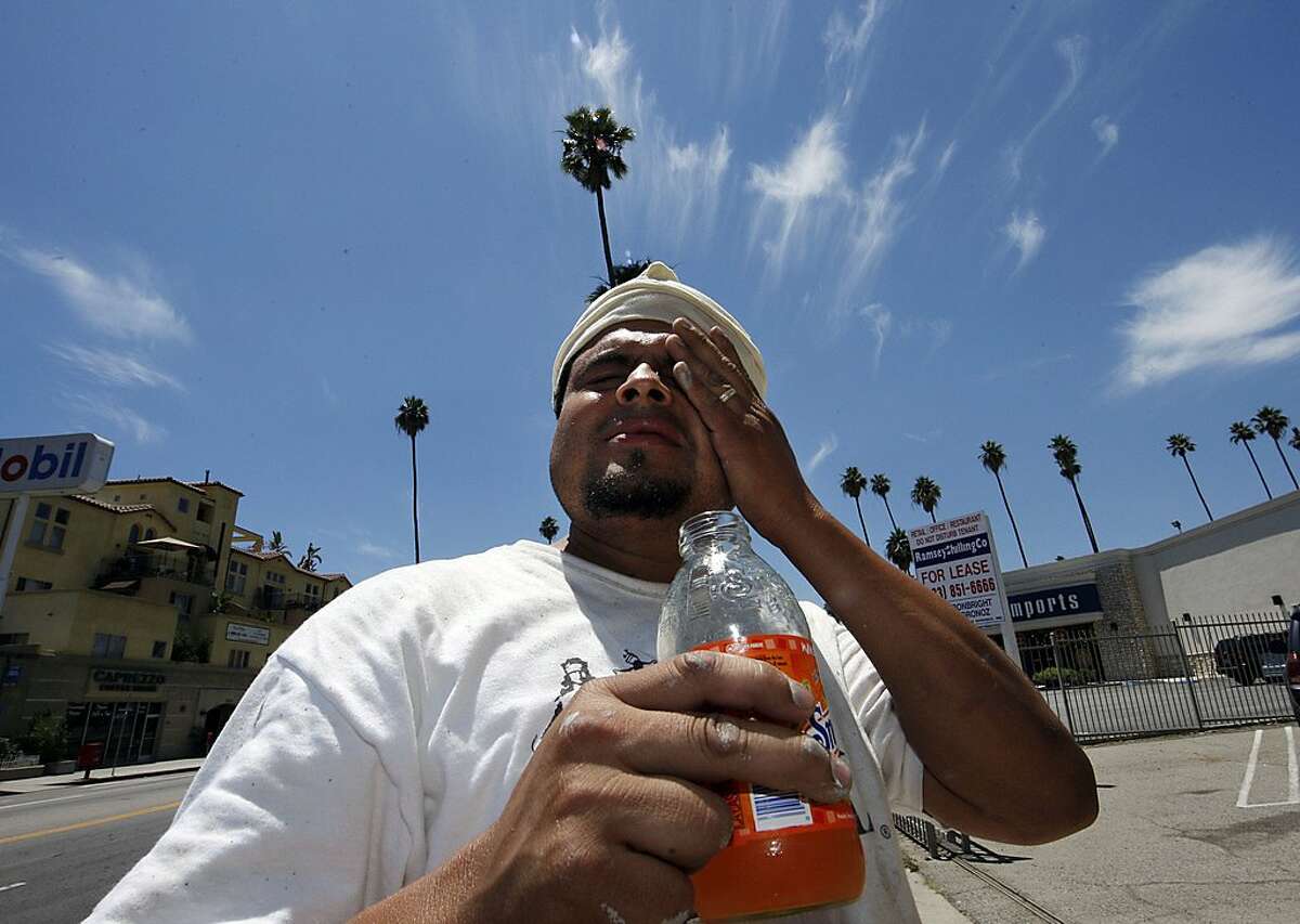 Wilfredo Aguilar wipes sweat from his forehead as he takes a break from painting a building under the hot sun on Hollywood Boulevard in Los Angeles, Thursday, June 19, 2008. Southern California roasted Thursday in a record-breaking, end-of-spring heat wave that sent temperatures soaring past 100 degrees in many areas, posing hazards for anyone who ventured outside. (AP Photo/Kevork Djansezian)